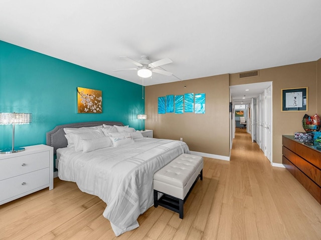 bedroom with ceiling fan, an accent wall, visible vents, baseboards, and light wood-type flooring