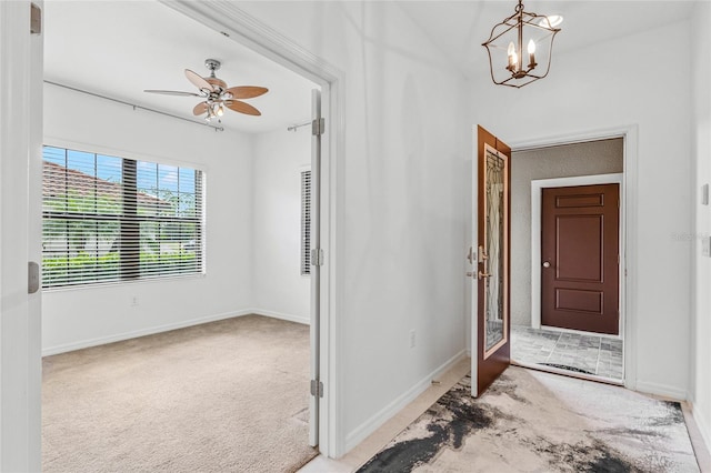 carpeted entryway with ceiling fan with notable chandelier