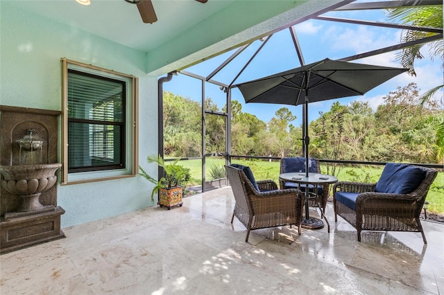 view of patio with ceiling fan and glass enclosure