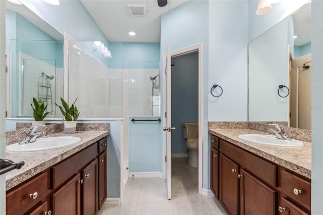 bathroom featuring vanity, tiled shower, toilet, and tile patterned flooring