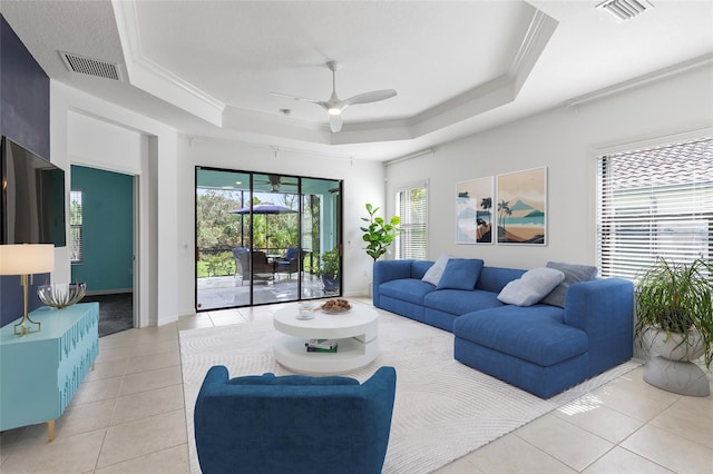 tiled living room featuring ceiling fan, a raised ceiling, and ornamental molding