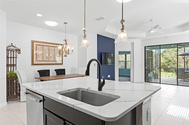 kitchen featuring sink, a tray ceiling, stainless steel dishwasher, pendant lighting, and a kitchen island with sink