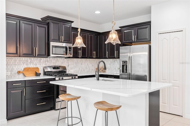 kitchen with an island with sink, stainless steel appliances, sink, a breakfast bar, and pendant lighting