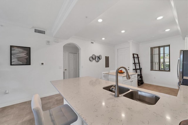 kitchen featuring sink, stainless steel fridge, crown molding, white cabinets, and light stone counters