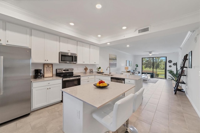 kitchen with kitchen peninsula, ceiling fan, a breakfast bar, sink, and stainless steel appliances