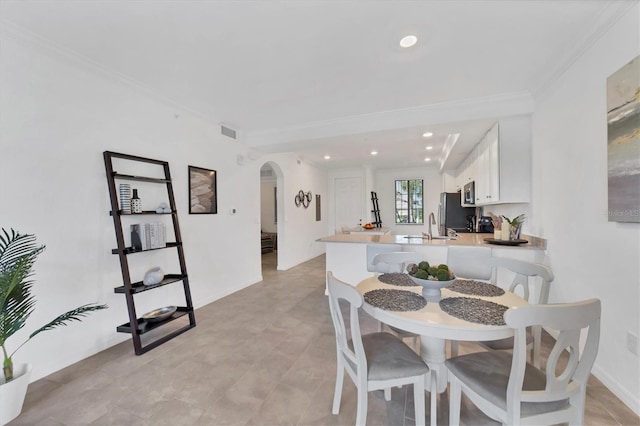 dining space with ornamental molding and sink