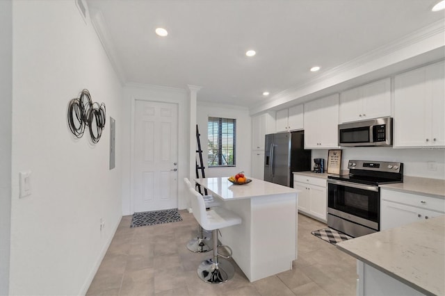 kitchen with a kitchen island, a breakfast bar area, stainless steel appliances, ornamental molding, and white cabinets