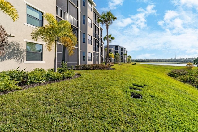 view of home's community with a water view and a lawn