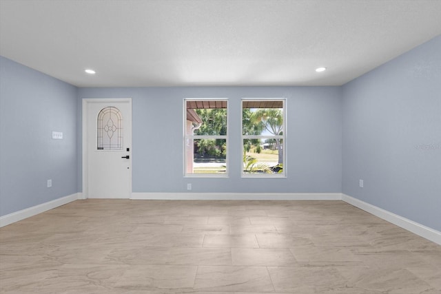 spare room with recessed lighting and baseboards