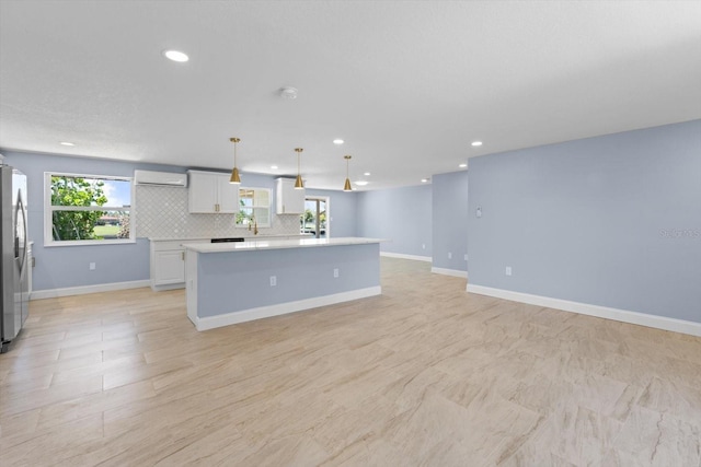 kitchen with light countertops, freestanding refrigerator, a center island, tasteful backsplash, and a wall mounted air conditioner