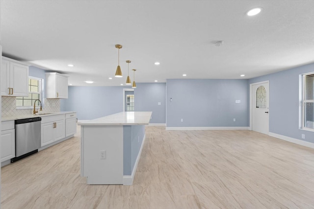 kitchen featuring a sink, white cabinetry, baseboards, stainless steel dishwasher, and decorative backsplash