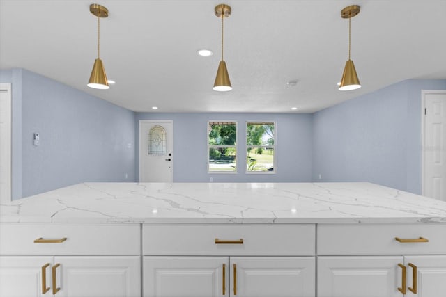 kitchen with light stone countertops, white cabinetry, and pendant lighting