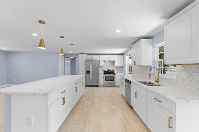 kitchen featuring stainless steel appliances, tasteful backsplash, sink, white cabinetry, and decorative light fixtures