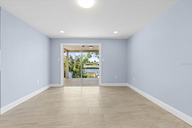 spare room featuring recessed lighting and baseboards