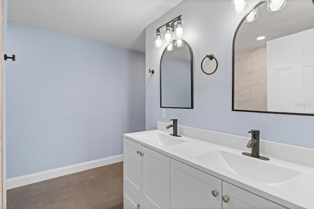 bathroom featuring wood finished floors, a sink, baseboards, and double vanity