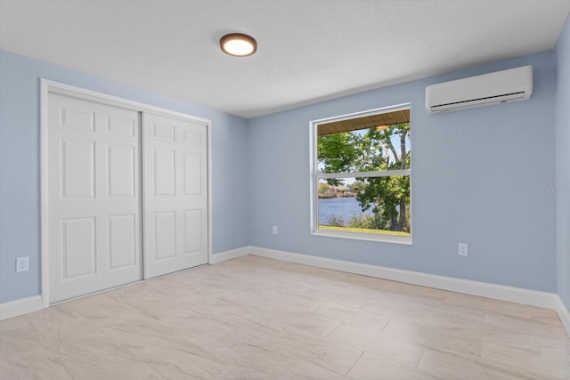 unfurnished bedroom featuring a closet, a wall unit AC, and baseboards