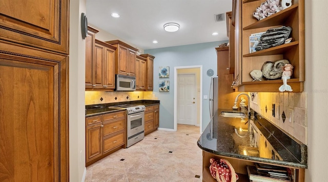 kitchen featuring appliances with stainless steel finishes, dark stone counters, decorative backsplash, and sink