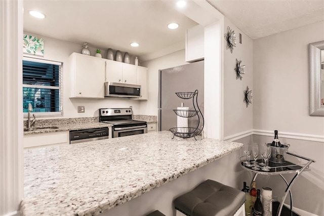 kitchen featuring light stone countertops, appliances with stainless steel finishes, sink, and white cabinetry