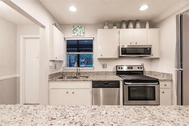 kitchen featuring white cabinets, appliances with stainless steel finishes, sink, and light stone counters