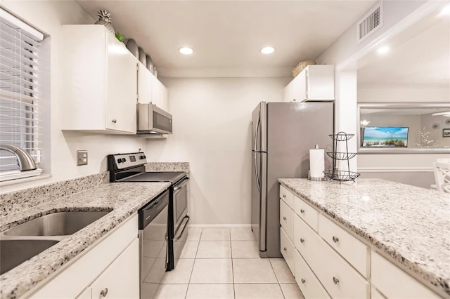 kitchen featuring light stone counters, white cabinets, sink, appliances with stainless steel finishes, and light tile patterned floors