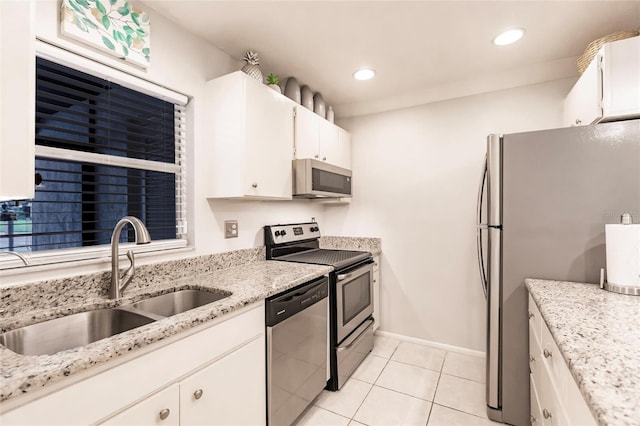 kitchen with sink, light stone countertops, white cabinets, appliances with stainless steel finishes, and light tile patterned floors