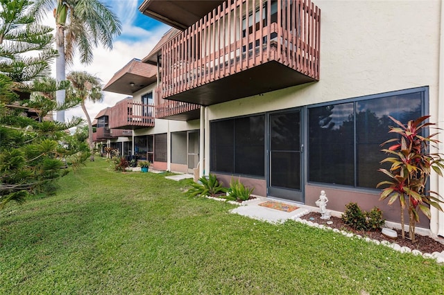 back of property with a balcony and a lawn