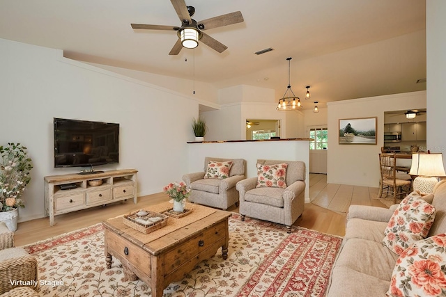 living room featuring ceiling fan with notable chandelier, light wood-type flooring, and lofted ceiling