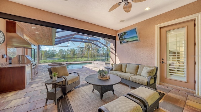 view of patio / terrace with a lanai, a ceiling fan, an outdoor pool, an outdoor kitchen, and outdoor lounge area