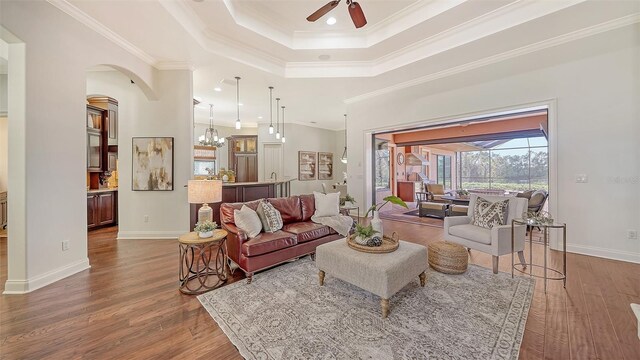 living room featuring a ceiling fan, wood finished floors, a tray ceiling, and ornamental molding