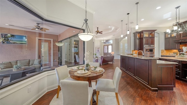 dining space with ceiling fan with notable chandelier, crown molding, sink, and dark hardwood / wood-style floors