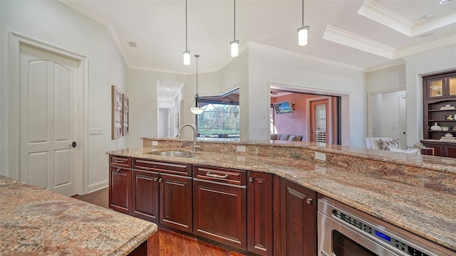 kitchen with light stone countertops, a sink, dark wood finished floors, built in microwave, and pendant lighting