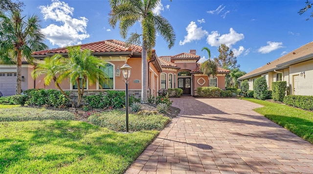 mediterranean / spanish house with a front lawn, stucco siding, a tiled roof, and a chimney