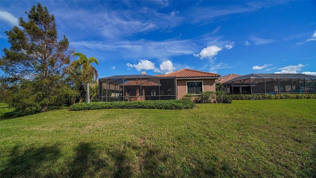 rear view of property featuring a yard and glass enclosure