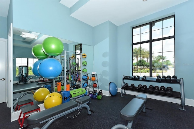 workout room with baseboards, a skylight, and a healthy amount of sunlight