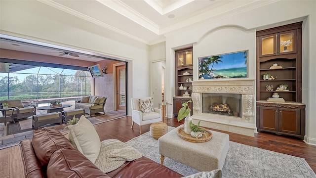 living area featuring ornamental molding, built in features, a sunroom, dark wood-style floors, and a premium fireplace