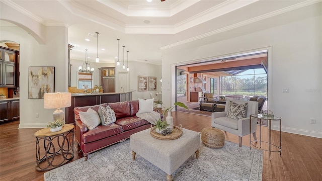 living room featuring a tray ceiling, ornamental molding, and wood finished floors
