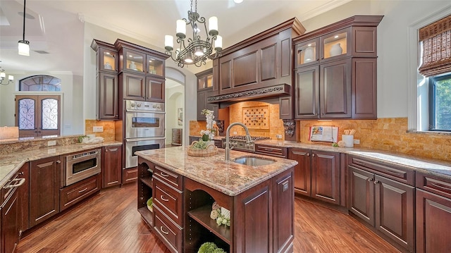 kitchen with an inviting chandelier, arched walkways, stainless steel appliances, and dark wood finished floors