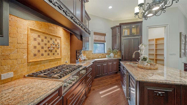kitchen featuring dark wood-style flooring, light stone countertops, glass insert cabinets, a sink, and stainless steel gas stovetop