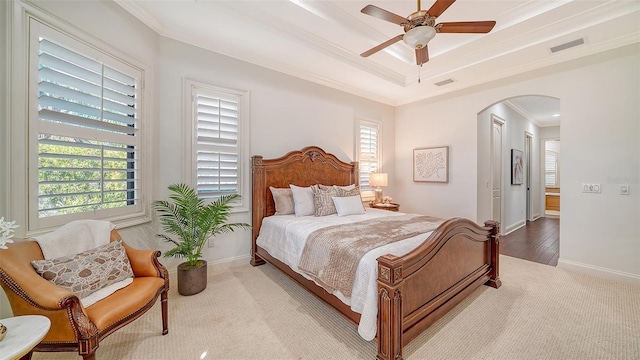 carpeted bedroom featuring arched walkways, ornamental molding, a raised ceiling, and visible vents