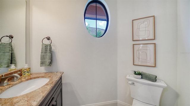 half bath featuring vanity, baseboards, and toilet