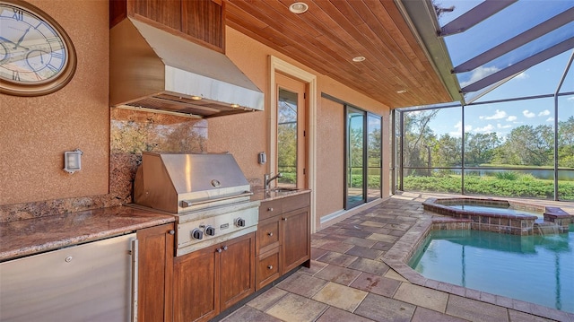 view of patio with an outdoor kitchen, area for grilling, a water view, a sink, and a lanai