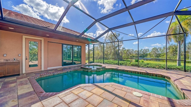 view of swimming pool featuring glass enclosure, a water view, a pool with connected hot tub, and a patio area