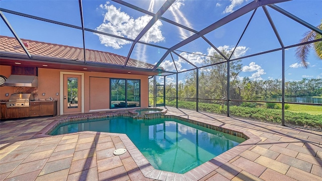 view of pool featuring a pool with connected hot tub, an outdoor kitchen, grilling area, a patio area, and a lanai