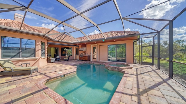 view of swimming pool with a lanai, a patio, a pool with connected hot tub, and an outdoor kitchen