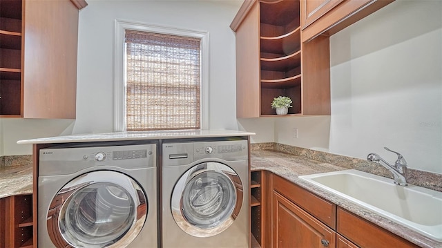 washroom with a sink, cabinet space, and independent washer and dryer