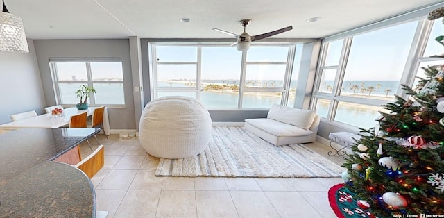 sunroom / solarium with ceiling fan and a water view