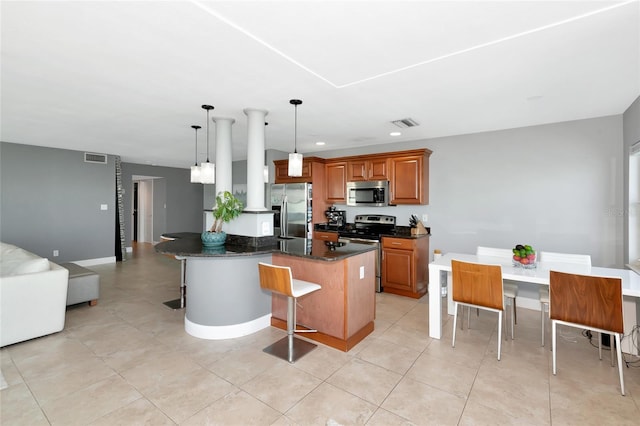 226 Golden Gate Pt Unit 64, Sarasota, FL 34236 - kitchen featuring recessed lighting, a kitchen breakfast bar, stainless steel appliances, brown cabinetry, and hanging light fixtures