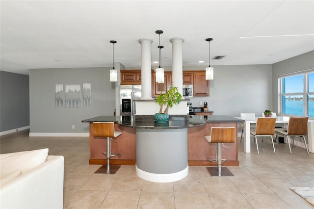 226 Golden Gate Pt Unit 64, Sarasota, FL 34236 - kitchen with stainless steel appliances, a kitchen breakfast bar, visible vents, brown cabinetry, and a kitchen island