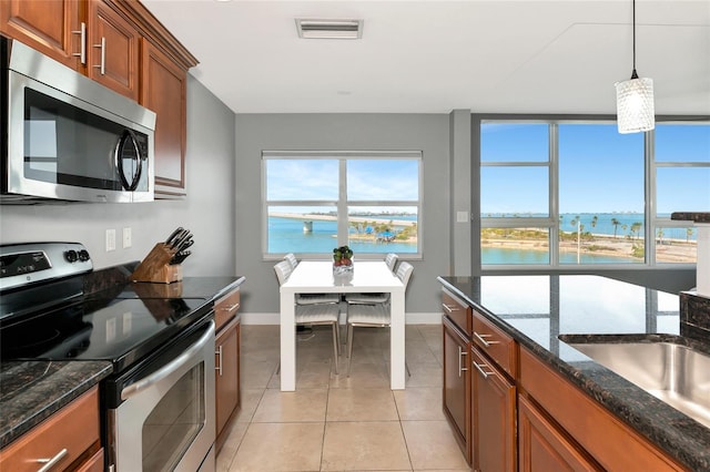 226 Golden Gate Pt Unit 64, Sarasota, FL 34236 - kitchen featuring stainless steel appliances, a water view, baseboards, visible vents, and brown cabinets