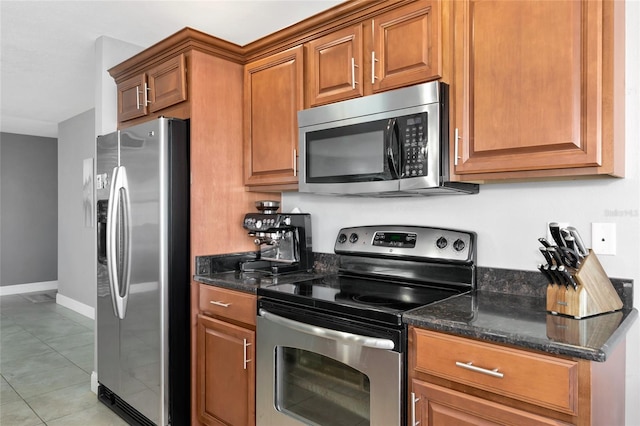 226 Golden Gate Pt Unit 64, Sarasota, FL 34236 - kitchen featuring brown cabinets, dark stone counters, baseboards, and stainless steel appliances
